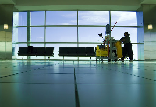 janitor pushing a trolley of cleaning equipment